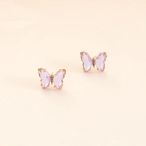 Detail view of purple zircon butterfly earrings with golden claw setting on beige background
