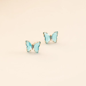 Macro shot of blue butterfly earrings with gold frame and sparkling crystals details