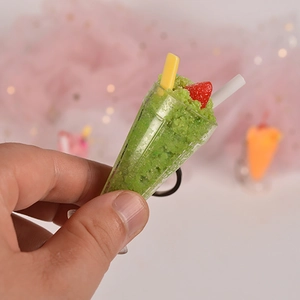 Miniature green ice drink charm with red strawberry and straw detail held in hand