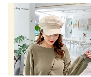 Detail view of a beige cotton linen newsboy hat on a model in a stylish cafe setting