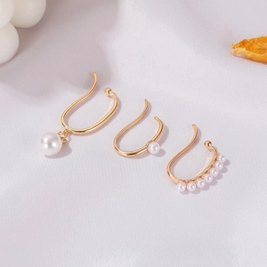 Detailed macro shot of three vintage gold pearl ear cuffs on a soft white fabric