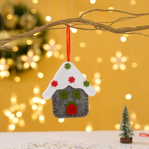 Handmade felt snow cottage Christmas tree ornament hanging on branch with warm lights