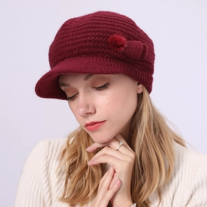 Details der burgunderroten Strickmütze mit Schirm und dekorativem weichem Bommel