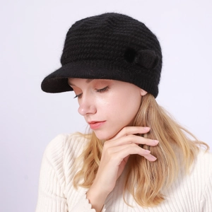 Detailaufnahme der schwarzen Strickmütze mit Schirm, Grobgarnstruktur und seitlichem Bommel