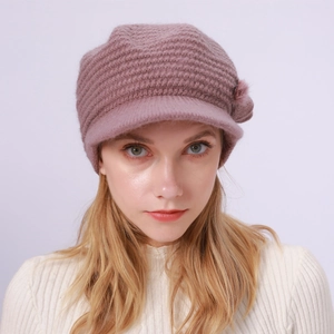 Detail einer zartrosa Strickmütze mit Schirm und flauschigem Bommel für Damen