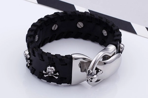 Detail of black leather punk bracelet featuring silver skull studs and large metal buckle