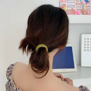 Minimalist light green acetate circular hair ring accessory on woman's ponytail