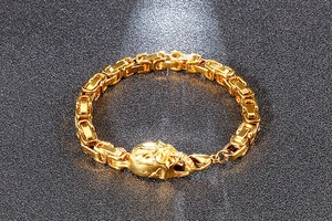 Detail of a golden Byzantine chain bracelet featuring punk skull charms and lobster clasp