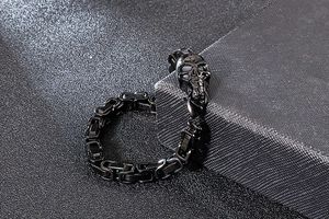 Detail view of gothic black stainless steel skull link bracelet with punisher style charm