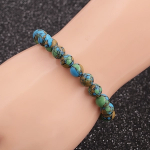 Detailed view of beaded bracelet with blue-green marble patterns on elastic cord