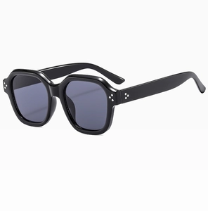 Detail shot of irregular black sunglasses with silver rivet accents and dark lenses