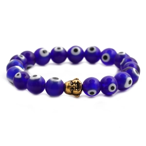 Detailed shot of blue evil eye beads with a golden buddha head on the bracelet