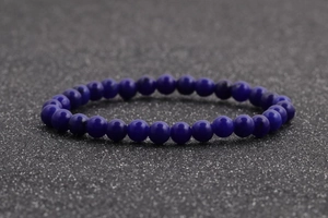 Vista macro de cuentas de ágata azul profundo de 6mm en una pulsera elástica con textura de piedra
