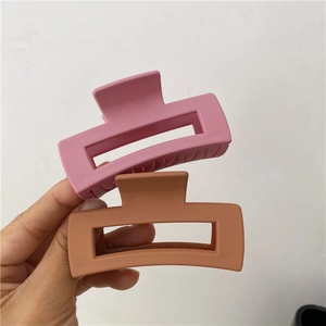 Matte pink and brown hollow geometric plastic hair claws held for size display