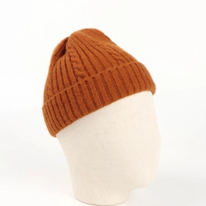 Close-up of dark brown cable knit beanie showing thick wool texture and folded cuff detail