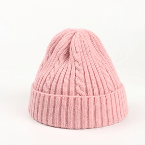 Close-up of pink cable knit beanie showing thick ribbed cuff and textured wool pattern