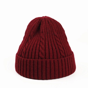 Macro detail of wine red cable knit texture and ribbed cuff on a warm winter beanie