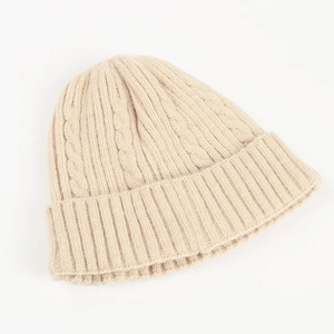 Detail of beige cable knit beanie showing thick warm texture and ribbed folded cuff