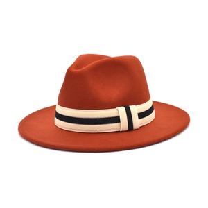 Close-up of burnt orange wool fedora hat featuring a black and white striped woven band