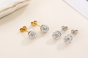 Détail de boucles d'oreilles dorées et argentées avec boules en zircone et argile blanche