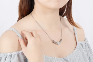 Gros plan d'un collier en maille serpent argentée avec perle en zircone et billes d'acier