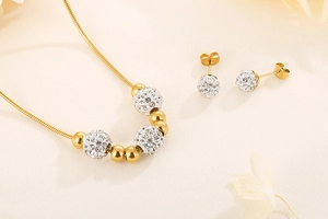 Détail de parure collier et boucles d'oreilles dorées avec perles de cristal blanc