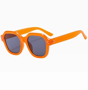 Close-up of bright orange hexagonal sunglasses with silver rivets and grey lenses