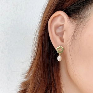 Detail of 925 silver flower stud earring with white baroque pearl on model's ear