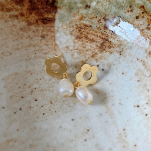 Macro shot of 925 silver flower earrings with white pearls on rustic ceramic plate
