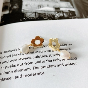 Macro shot of gold floral earrings with teardrop pearls on fashion magazine pages