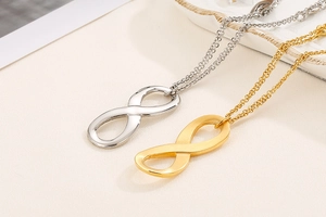 Close-up of infinity symbol necklaces in gold and silver finish on a ceramic tray