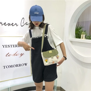 Détail du sac bandoulière en toile avec écussons ours et tournesol et rabat vert