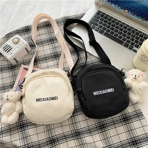 Detailed view of canvas crossbody bags in black and beige with plush bear charms