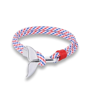 Macro detail of nautical rope bracelet with silver whale tail charm in red white blue colors