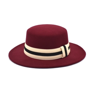 Detail eines weinroten flachen Fedora-Hutes mit gestreiftem beige-schwarzem Band