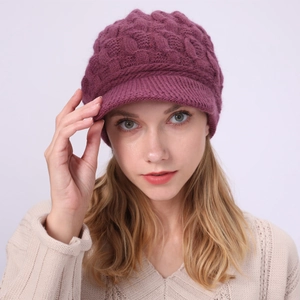 Detalle de un gorro de punto trenzado color burdeos con visera para otoño e invierno