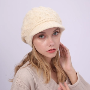 Primer plano de gorra tipo boina de punto trenzado beige con visera y textura gruesa