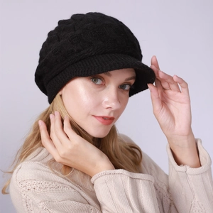 Detalle de gorra de punto trenzado negra con textura gruesa y visera para invierno