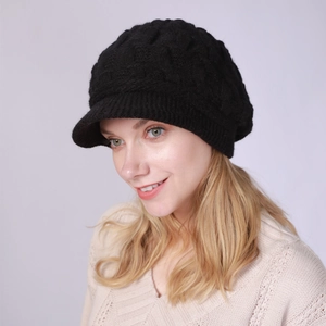 Detalle de gorro de punto de ochos negro con visera, textura de invierno y borde acanalado