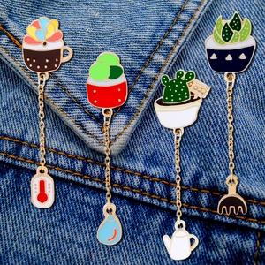 Detail of enamel succulent pins with golden chains and gardening themed charms
