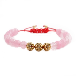 Macro detail of faceted pink beads and gold hollow pavé charms on adjustable red cord
