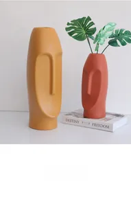 Close-up of matte ceramic face vases in mustard yellow and brick red for home decor