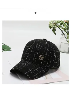 Detail of black and white tweed baseball cap with a gold metallic M emblem