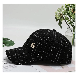Detailed shot of black and white tweed baseball cap with a gold metal M emblem logo