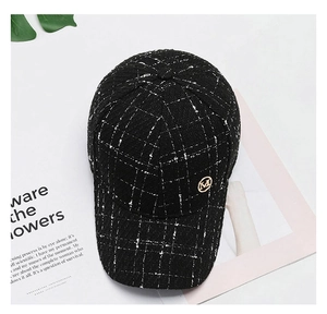 Detailed macro view of black and white tweed baseball cap with a gold M letter metal badge