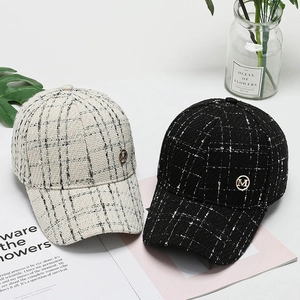 Close-up of tweed checkered baseball caps with metallic M logo and thick fabric texture