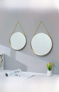 Close-up of minimalist round wall mirrors with gold metal frames and hanging chains