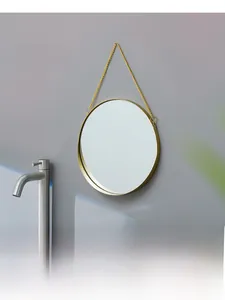Close-up of a Nordic round gold metal wall mirror with hanging chain for bathroom decor