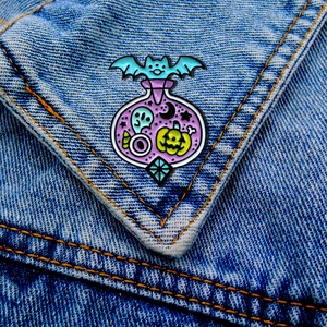 Halloween enamel pin set with bat, ghost and pumpkin charms on blue denim jacket