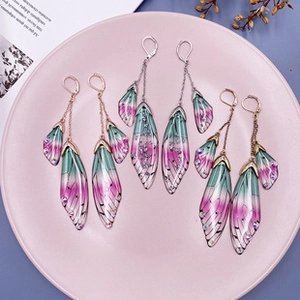 Detailed macro shot of gradient purple-green butterfly wing earrings with tiny rhinestones